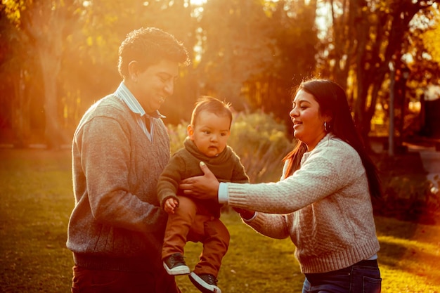 Father and mother with their little son in a park outdoors