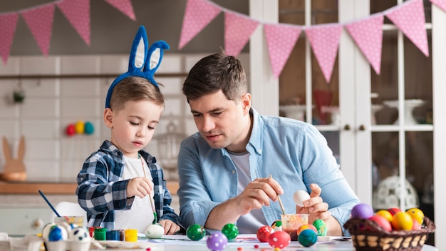 写真 イースターのための小さな男の子と父絵画卵