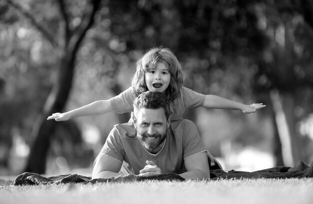 Father piggyback his little son outside lying on grass fathers day concept
