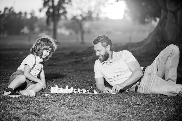 Отец играет в шахматы с семьей сына за пределами игры мальчик побеждает мужчину в шахматы