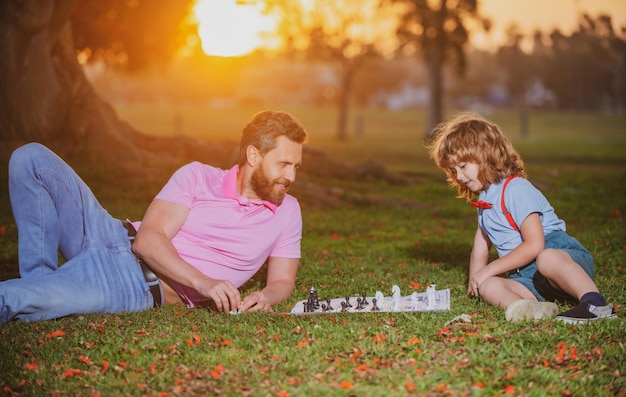 Father play chess with son family outside game young boy beating a man at chess