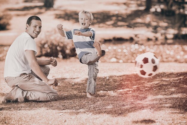 Father playing football with his son during the summer