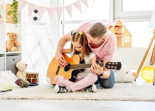 Father playing guitar with cute daughter