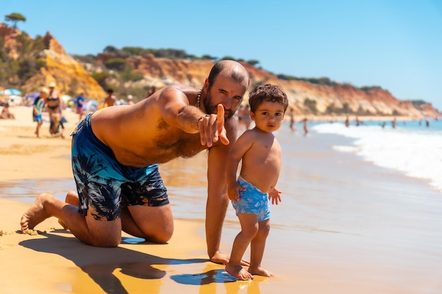 Father playing in the sand Praia do Barranco das Belharucas beach Albufeira Algarve Portugal