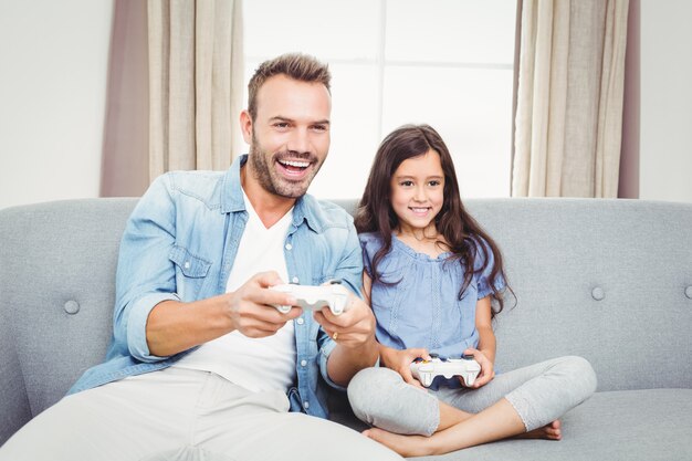 Father playing video game with his daughter at home