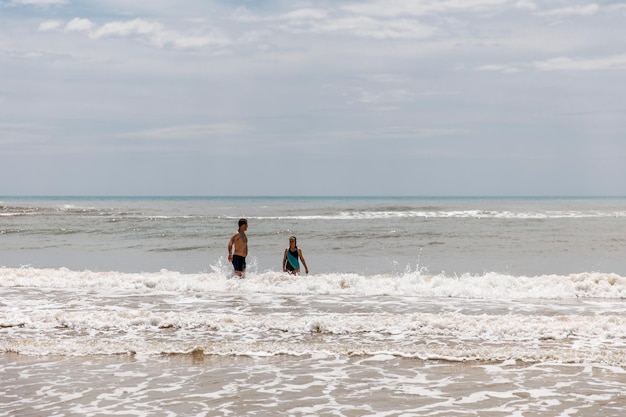 Отец играет в воде со своей дочерью на берегу моря