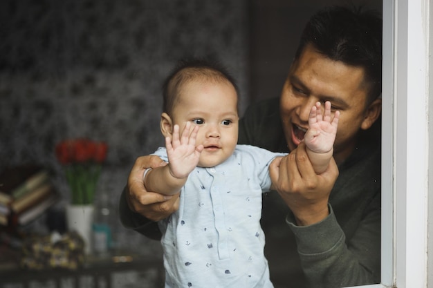 Father playing with cute baby boy inside the house