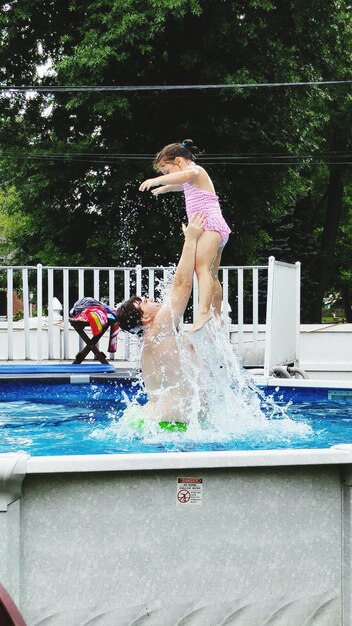 Photo father playing with daughter in washtub at backyard