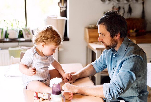 Father playing with little boy sitting on kitchen table