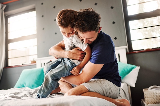 father playing with son on bed at home