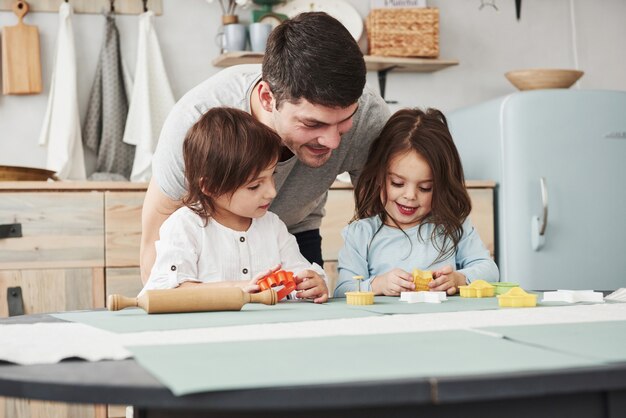 Padre che gioca con due ragazze in cucina. concezione della genitorialità