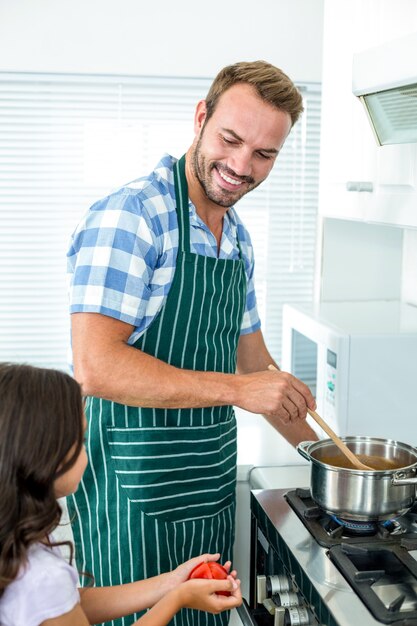 Father preparing food while daughter helping him in kitchen