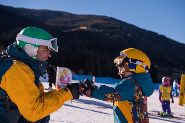 Foto padre che prepara il suo piccolo figlio per la prima volta su uno snowboard