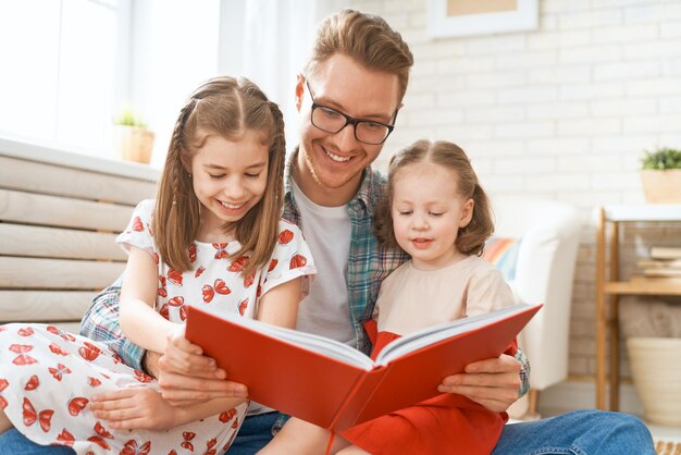 Father reading a book to his daughters