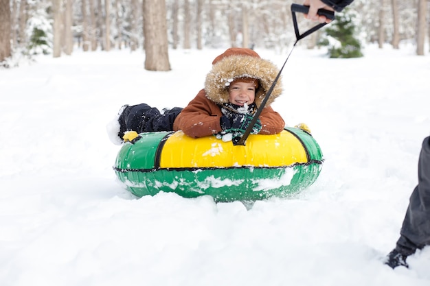 Photo father rides son on snow tube in winter