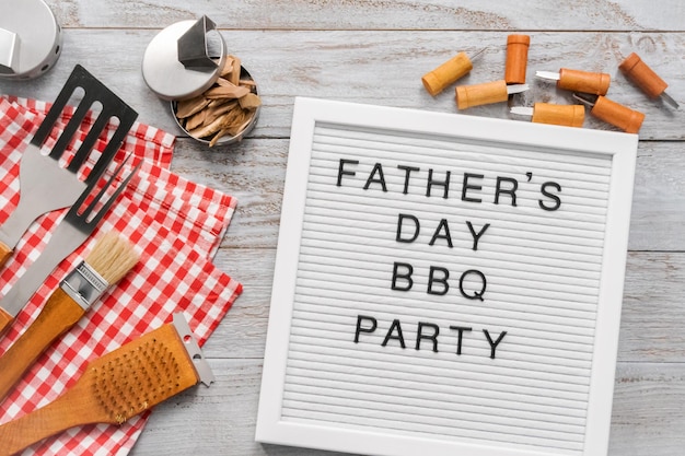 Father's Day BBQ Party sign on a white memo board with cooking tools.