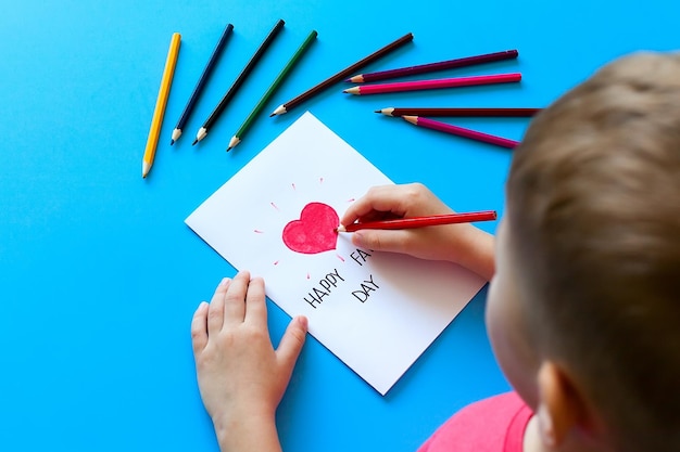 Father's day a boy draws a postcard to his father with pencils Children's love parents