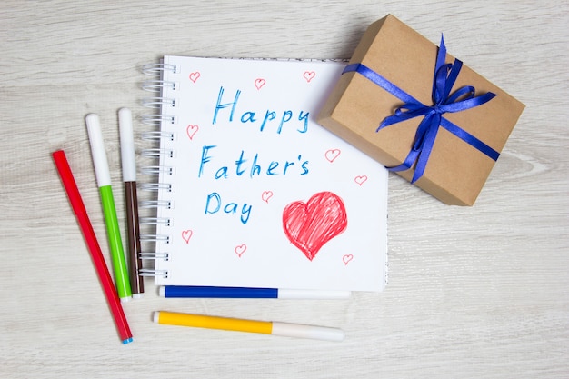Father's day. Children's drawing and gift. Gift box, drawing and colored markers.