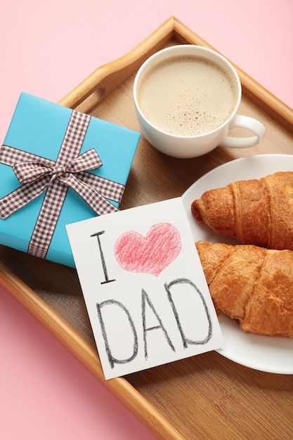 Concetto di festa del papà con carta regalo e colazione sul vassoio colazione per papà con croissant e caffè foto verticale