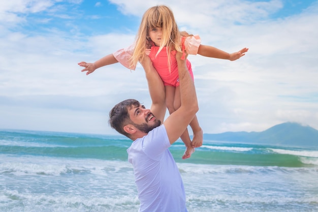 Father's day. Dad and child daughter playing together outdoors on a summer beach