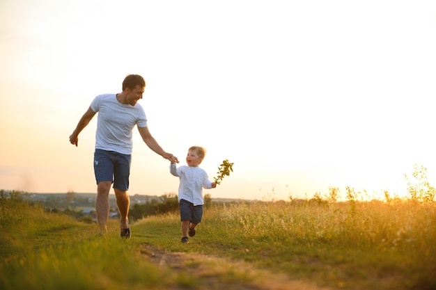 День отца Счастливый семейный отец и маленький сын играют и смеются на природе на закате
