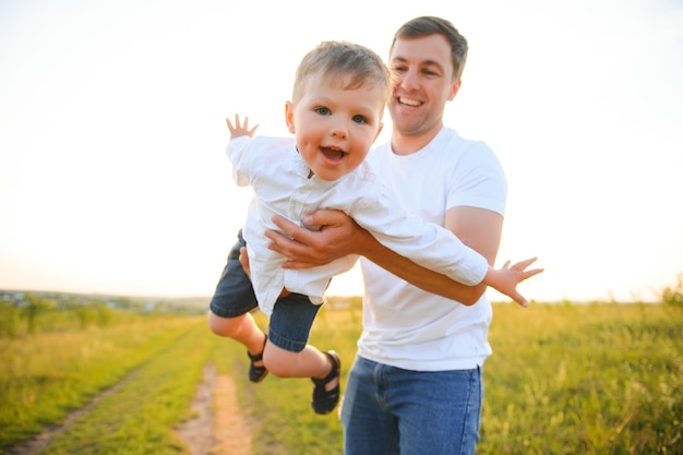День отца Счастливый семейный отец и маленький сын играют и смеются на природе на закате