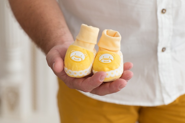 Father's hand holding  yellow  baby  booties