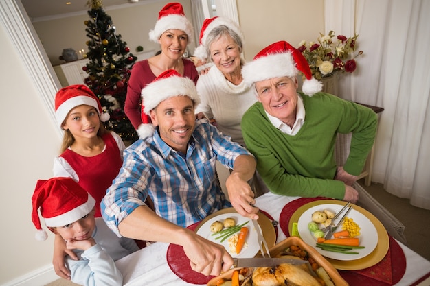 Father in santa hat carving chicken at christmas dinner