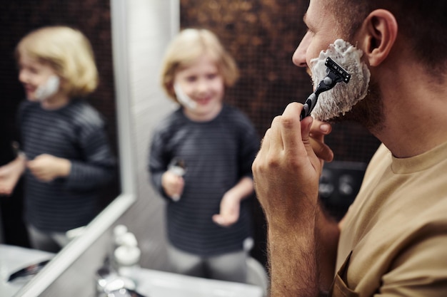 Photo father shaving beard closeup