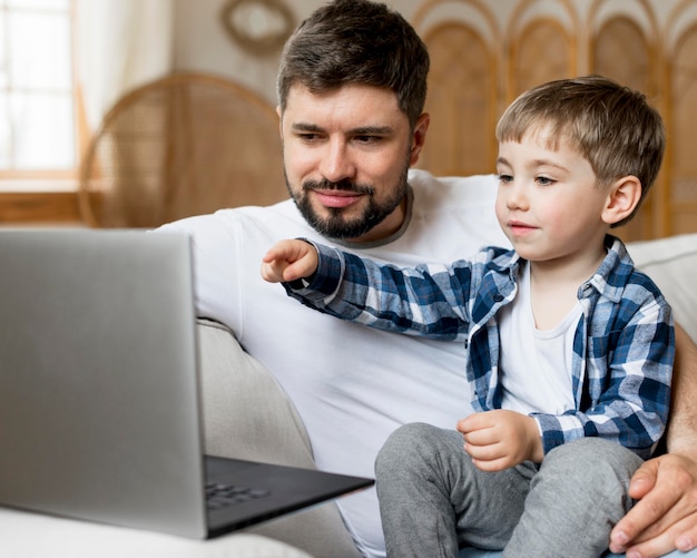 Foto padre seduto accanto a suo figlio e al lavoro