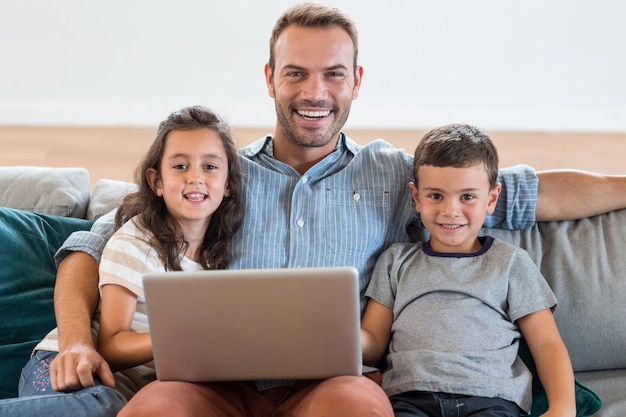 Father sitting on sofa with son and daughter