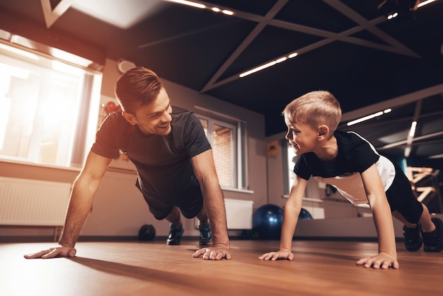 Father And Son Are Doing Push Ups In The Gym.