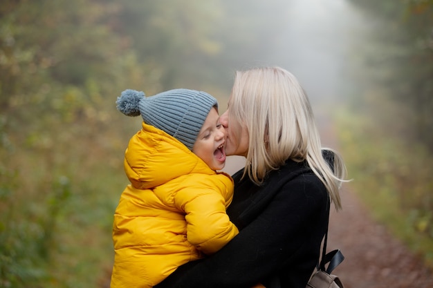 Father and son are have a fun in the autumn forest in fog