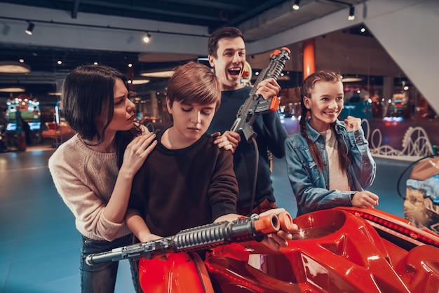 Father and son are shooting guns in arcade.