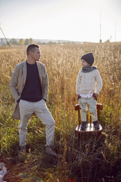 Father and son are standing on a field with dry grass outside the city