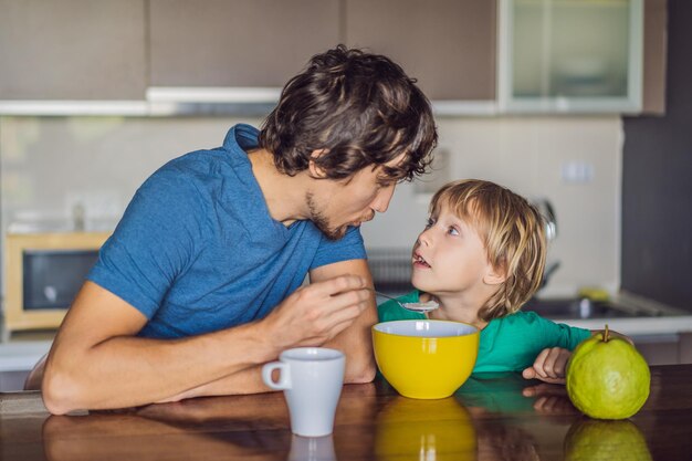 Father and son are talking and smiling while having a breakfast in kitchen