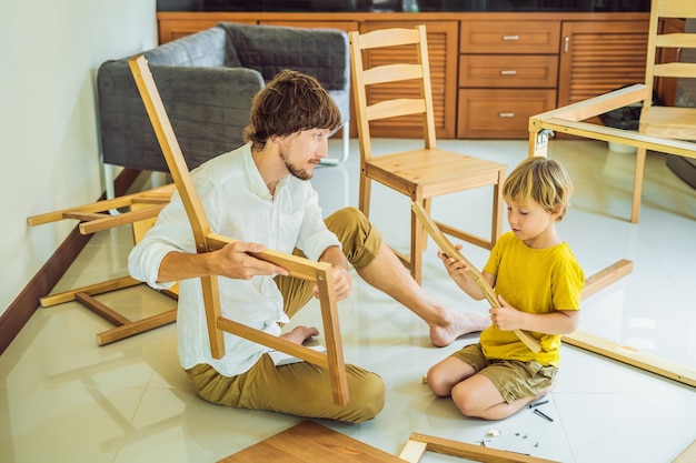 父と息子が家具を組み立てる少年が家で彼のお父さんを助ける幸せな家族の概念