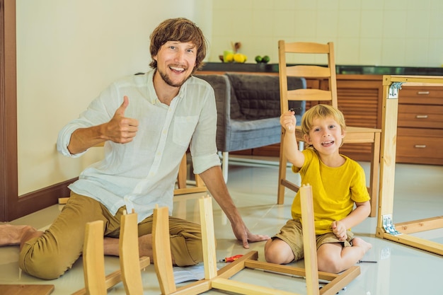 父と息子が家具を組み立てる少年が家で彼のお父さんを助ける幸せな家族の概念