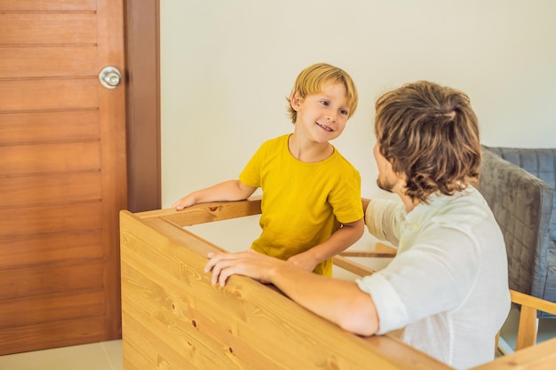 父と息子が家具を組み立てる少年が家で彼のお父さんを助ける幸せな家族の概念