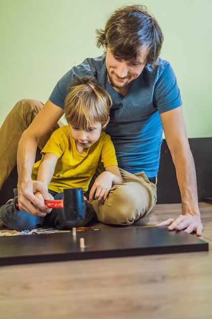 Father and son assembling furniture boy helping his dad at home\
happy family concept