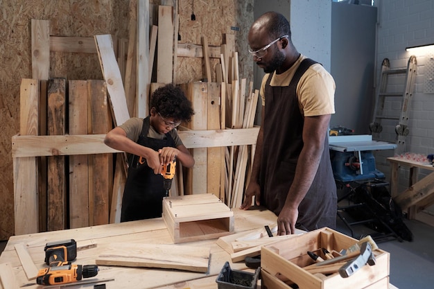 Father and son building birdhouse in workshop