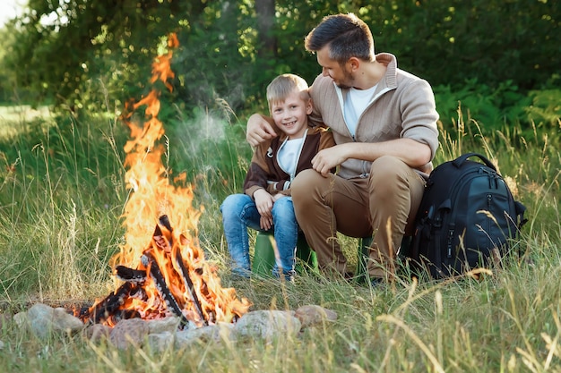 Father and son by the fire on green nature. 