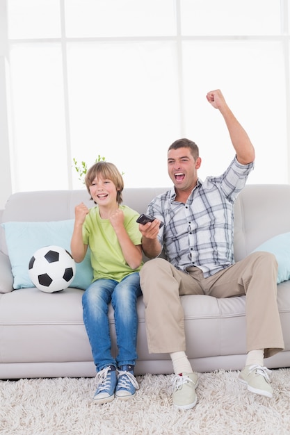 Отец и сын празднуют успех во время просмотра футбольного матча