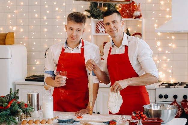 クリスマスキッチンの父と息子はクッキーを作るために生地を準備します