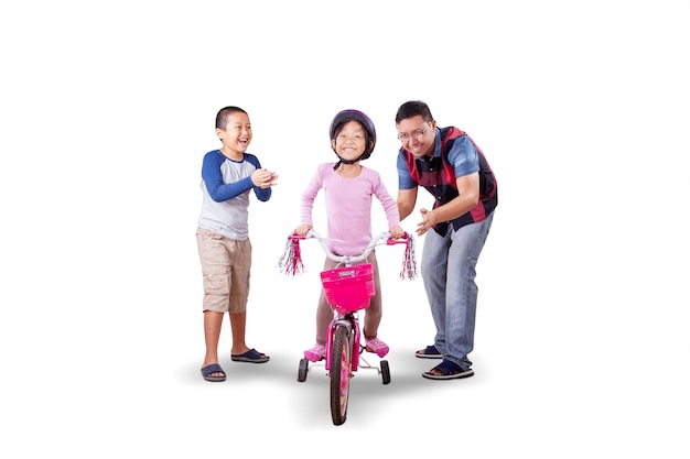 Father and son clapping for the girl riding a bike