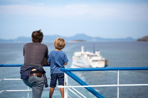 Father and son on a cruise vacation observing a ferry at sea