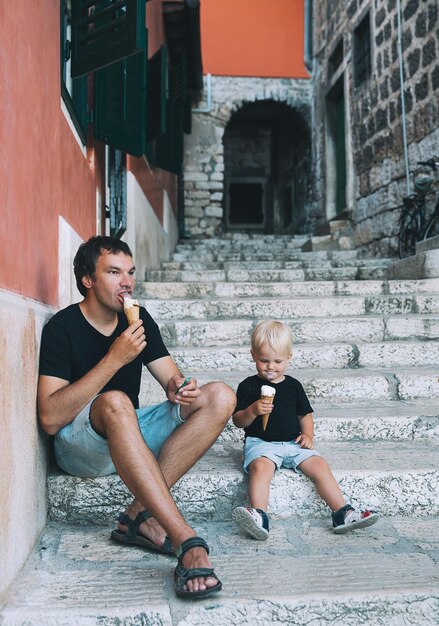 父と息子が一緒にアイスクリームを屋外で食べるイタリアの古い通りでジェラートと男と子の男の子愛する家族と夏休み