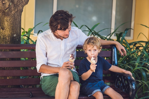 Father and son enjoying ice cream outside in a park.