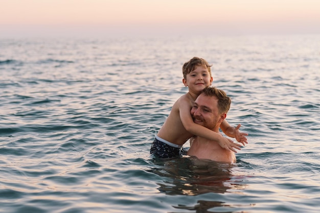 Father and son enjoying a swim in the ocean at dusk