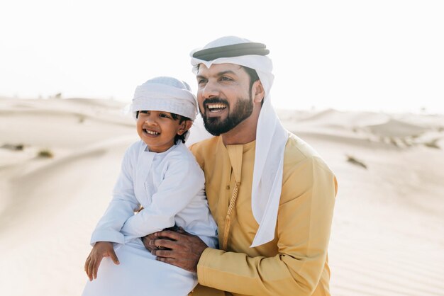 Photo father and son enjoying while kneeling in desert